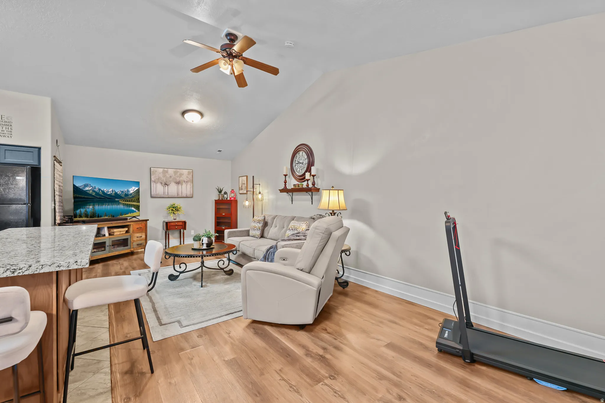 Living area featuring vaulted ceilings, wood-finish flooring, and a ceiling fan