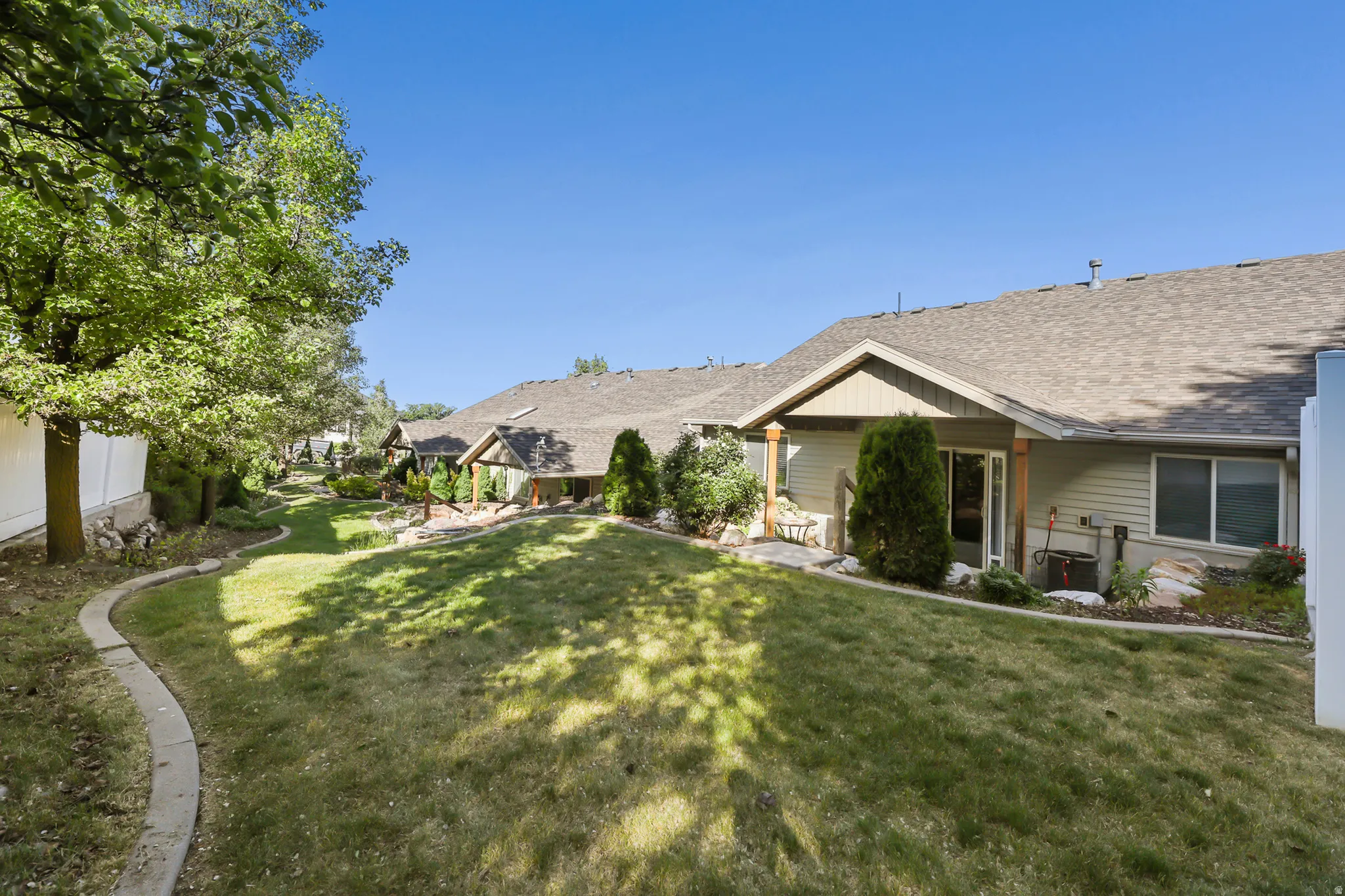 Expansive green lawn with a curved concrete border, mature trees, and shrubs