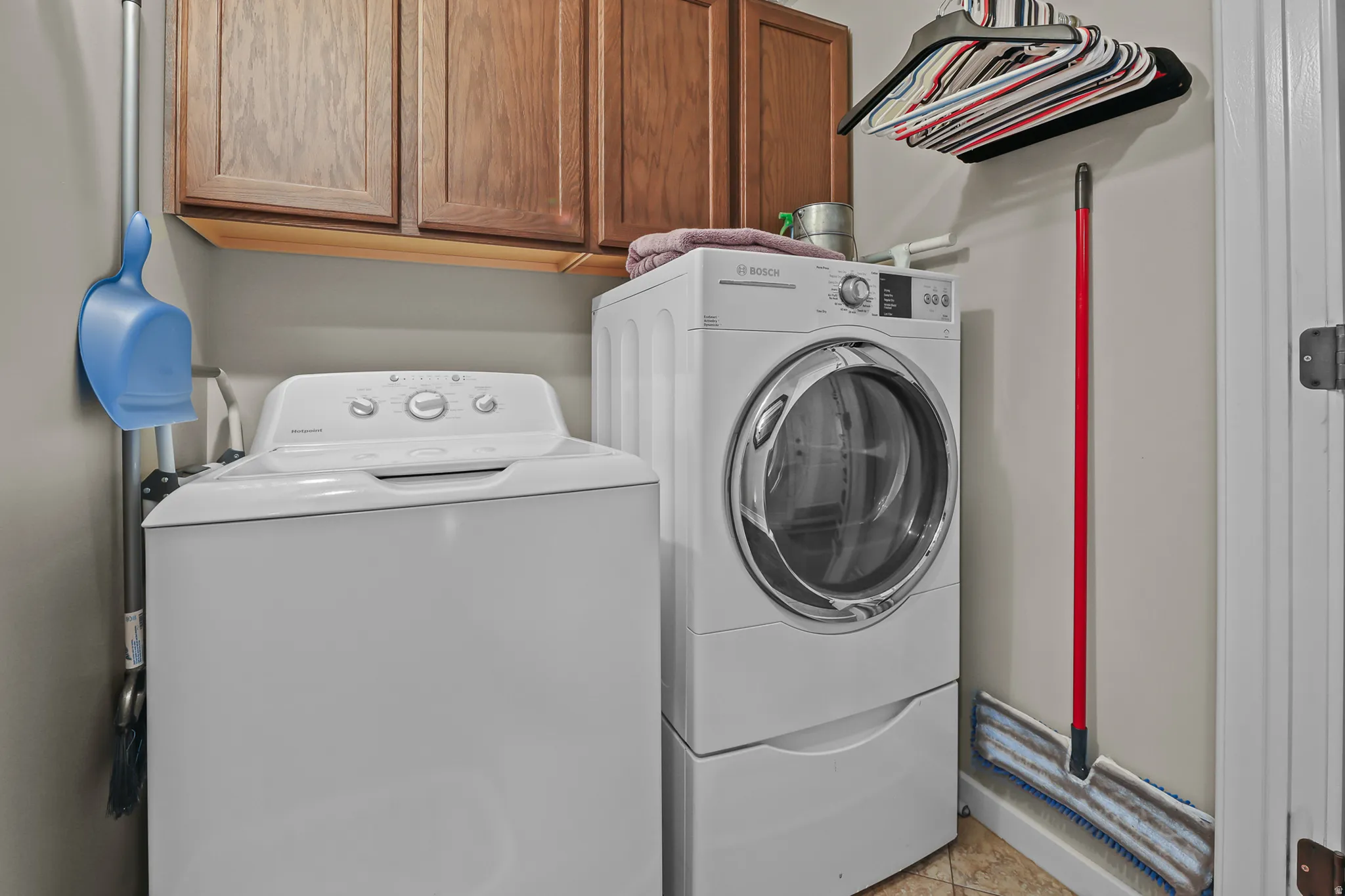 Laundry area featuring wood cabinetry, overhead shelving, and neutral wall tones