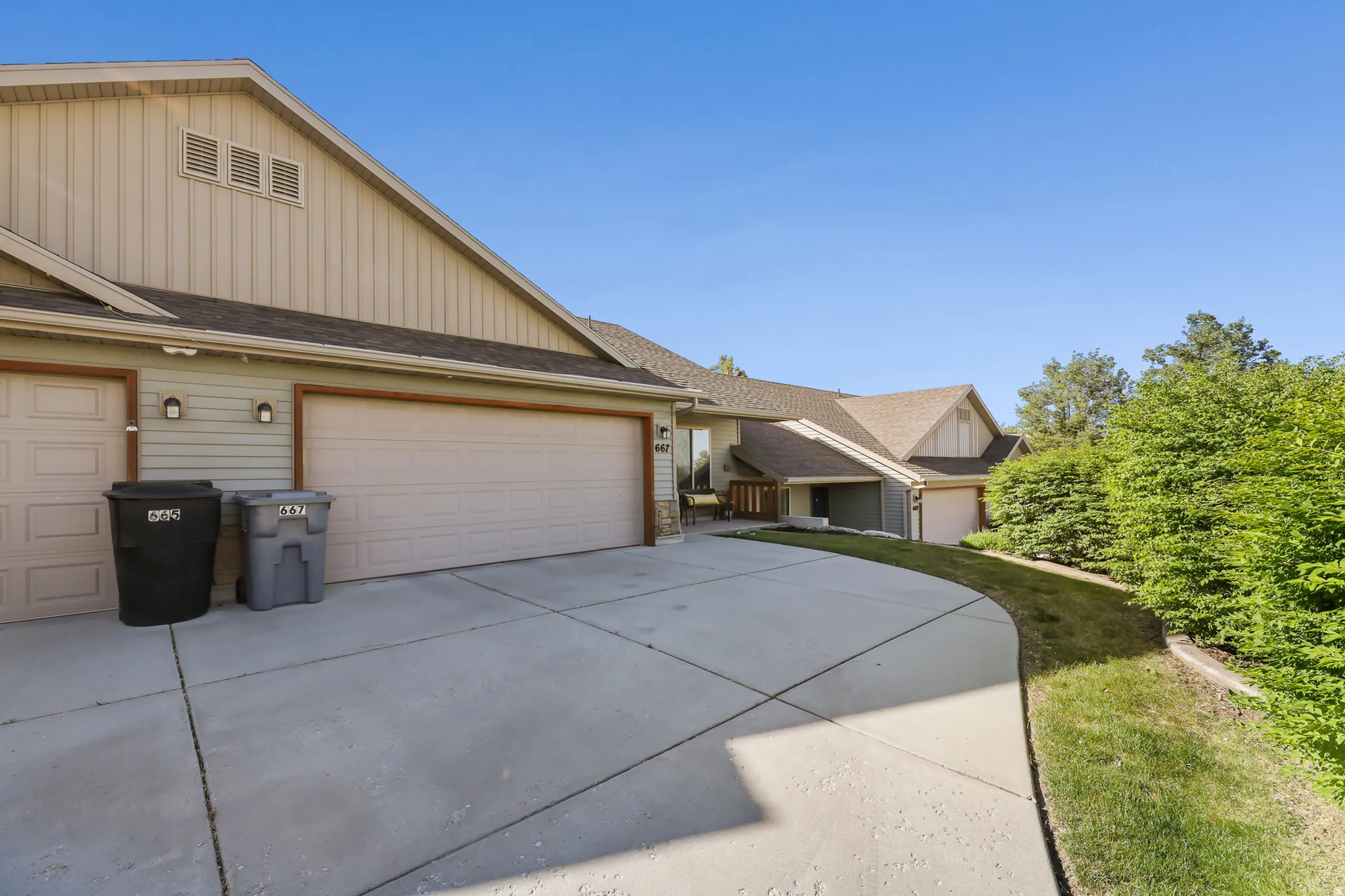 Expansive concrete driveway servicing a two-car garage with a single bay door and a larger double bay door