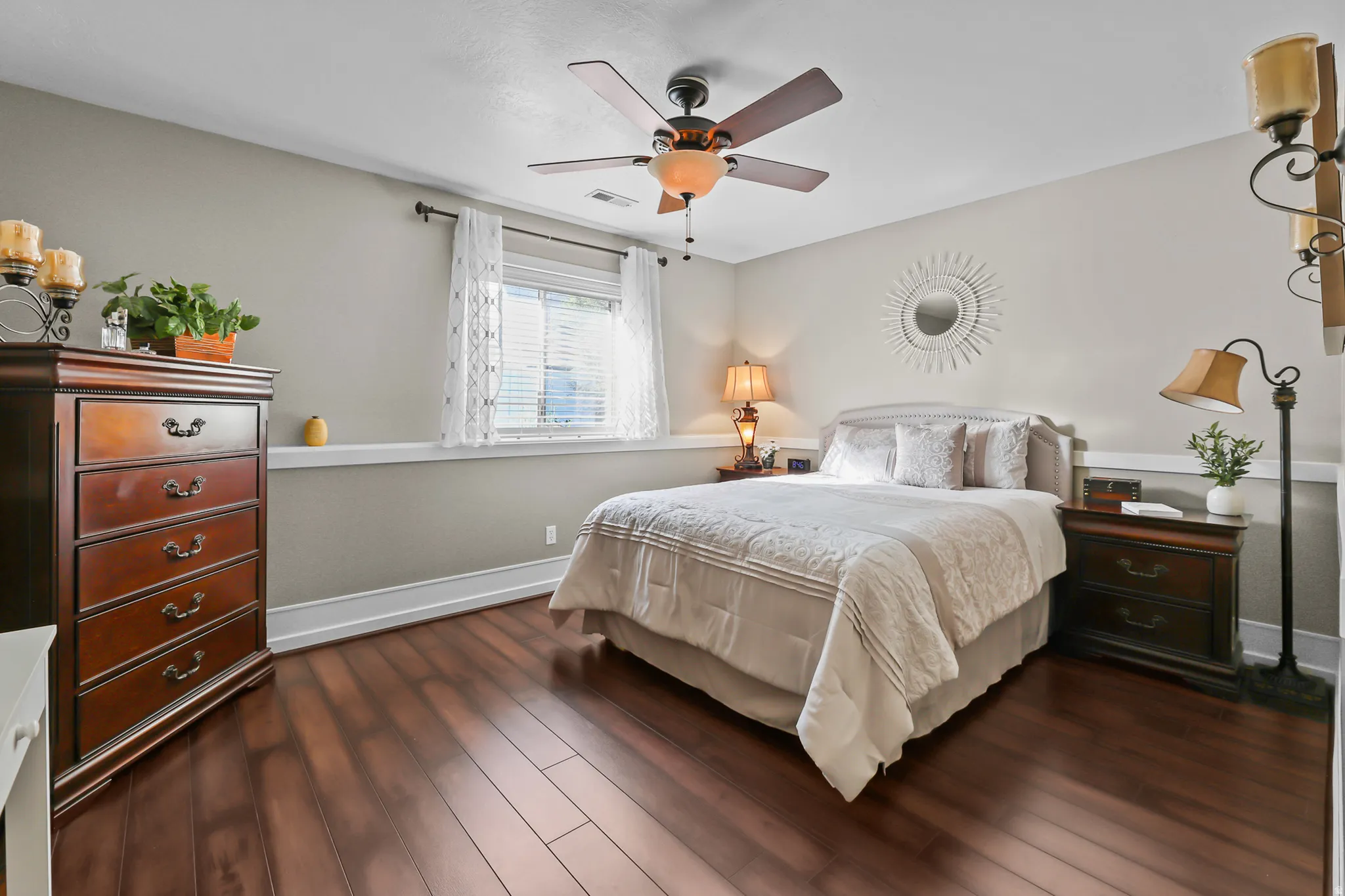 Spacious room featuring wood-finish flooring, a ceiling fan with integrated lighting, and a window with blinds