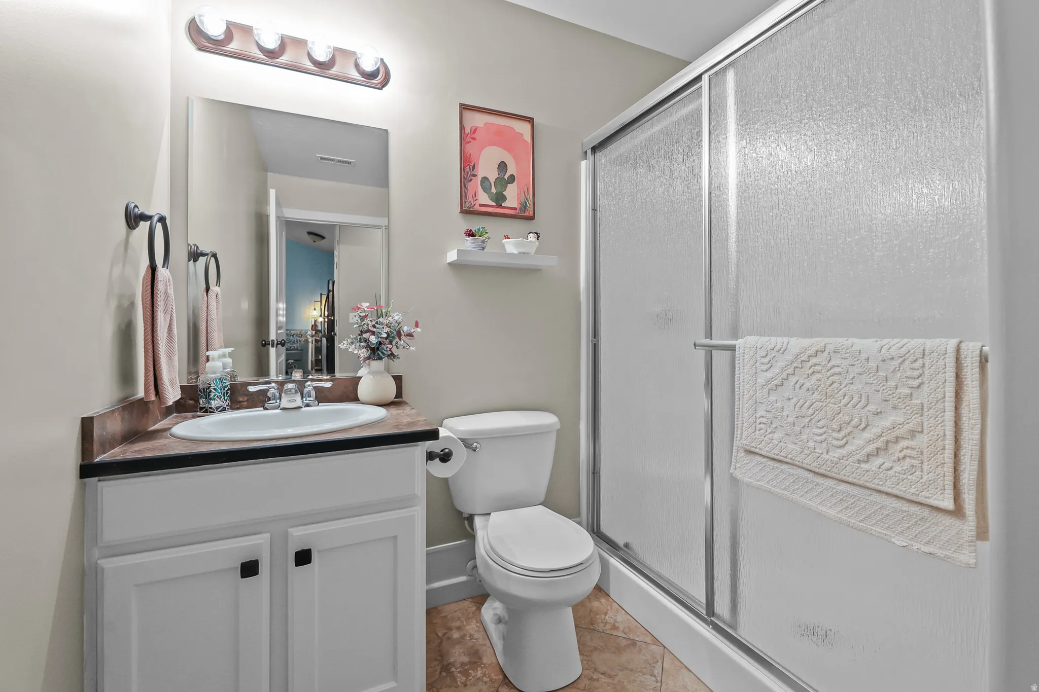 Bathroom featuring a white vanity with a brown countertop, an oval undermount sink, and a framed mirror