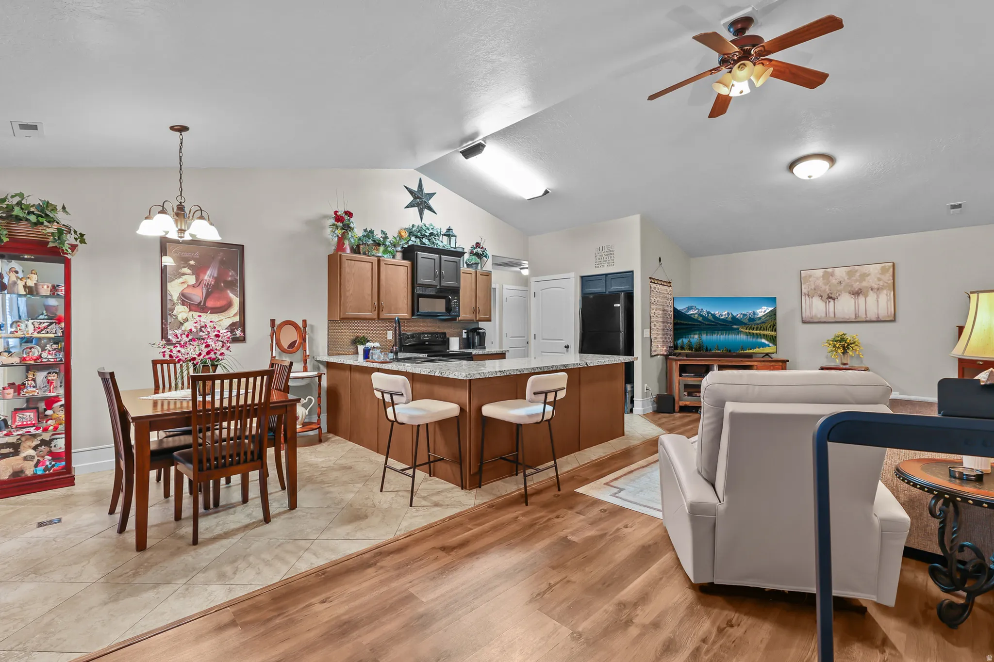 Open concept living space featuring vaulted ceilings, wood-finish flooring, and a kitchen with an extended counter