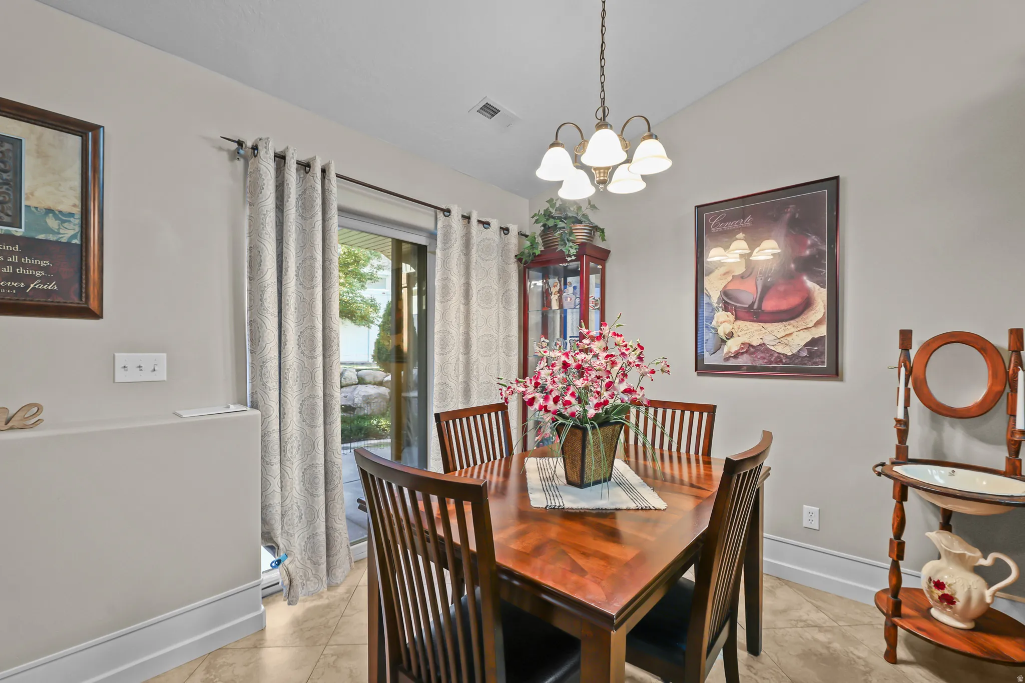 Dining area featuring warm-toned walls, tile flooring, and a sliding glass door with patterned curtains