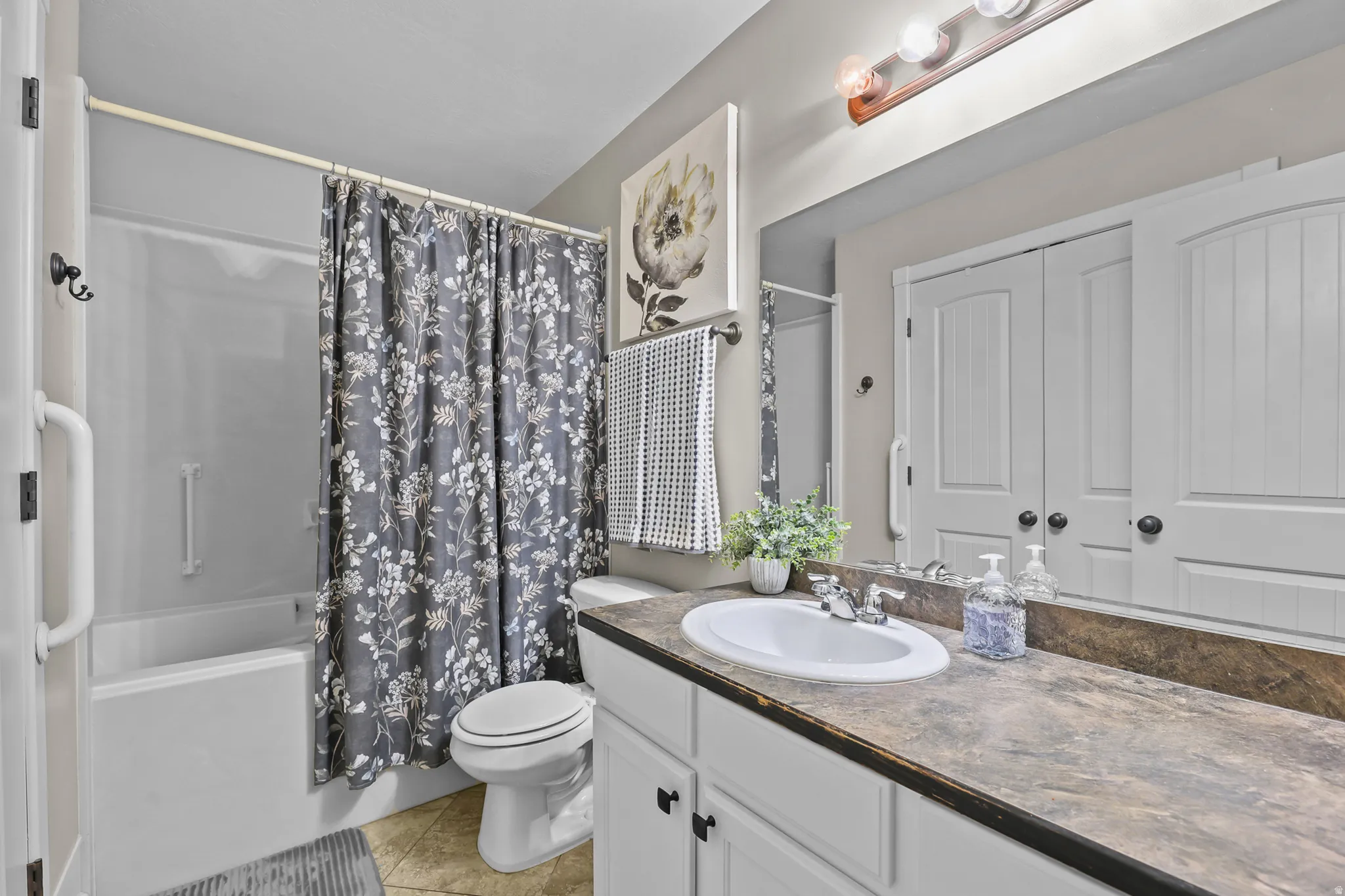 Full bathroom featuring a single vanity with an oval sink, a built-in bathtub with shower, and tile flooring