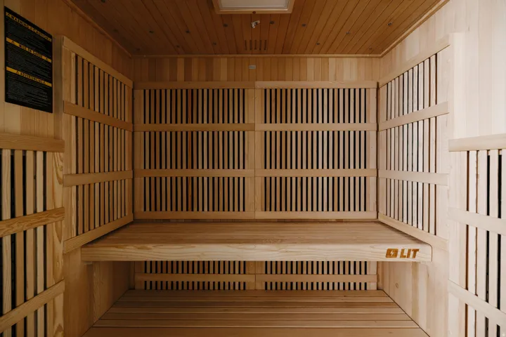 Built-in sauna featuring light wood paneling, slatted wall accents, a multi-level bench, and a wood plank floor