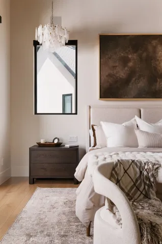 Bedroom featuring a clear glass chandelier, a black-framed window, light wood-finish flooring, and a dark wood-finish nightstand