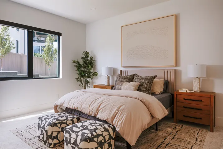 Bedroom featuring a large black-framed window, recessed ceiling lighting, a textured area rug, and wood-finish nightstands