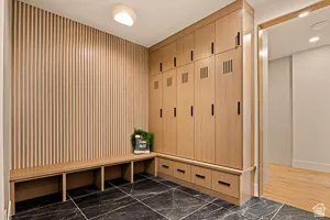 Built-in wood-finish cabinetry with black hardware, integrated bench seating, vertical slat wall paneling, and dark stone flooring with light veining