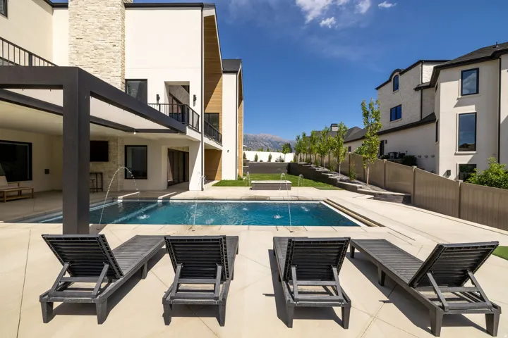 Rectangular swimming pool with integrated water features and expansive surrounding patio