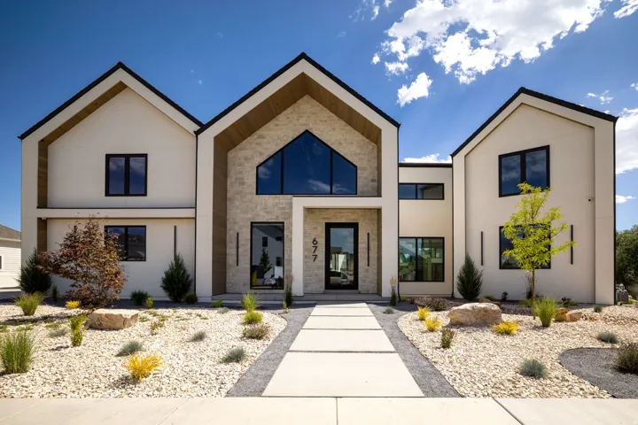 Modern exterior featuring a stone facade, prominent black-framed windows, and a clear glass entry door