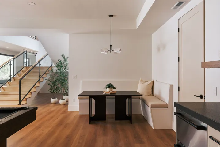 Open-concept dining area featuring a built-in banquette, contemporary chandelier, and wood-finish flooring