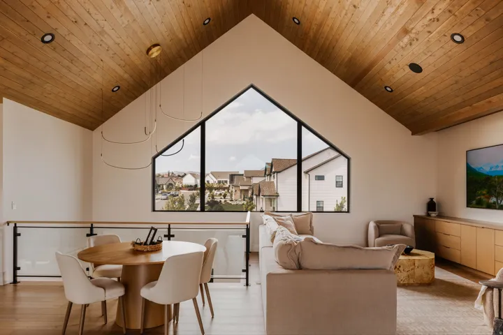 Vaulted wood-plank ceiling with recessed lighting and a striking triangular window
