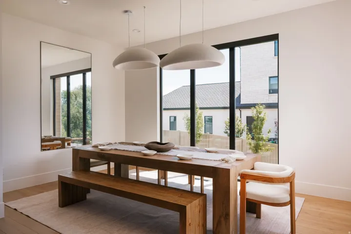 Dining area featuring light wood-finish flooring, white walls, and large black-framed windows