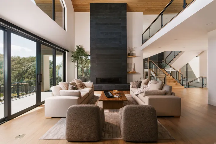 Two-story living area featuring a full-height stone-clad fireplace and wood-finish flooring
