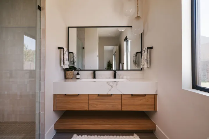 Modern bathroom featuring a floating wood-finish vanity with a marbled white countertop and integrated sink