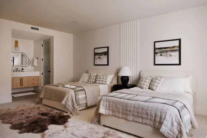Spacious room featuring two beds with upholstered headboards, recessed lighting, and wall paneling