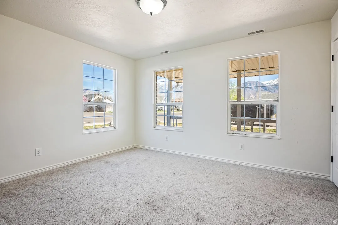 Interior room featuring light gray carpet flooring, white painted walls, and white baseboards