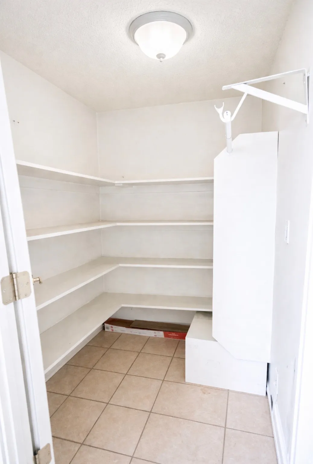 Ample pantry storage featuring wrap-around shelving, a ceiling-mounted light fixture, and ceramic tile flooring