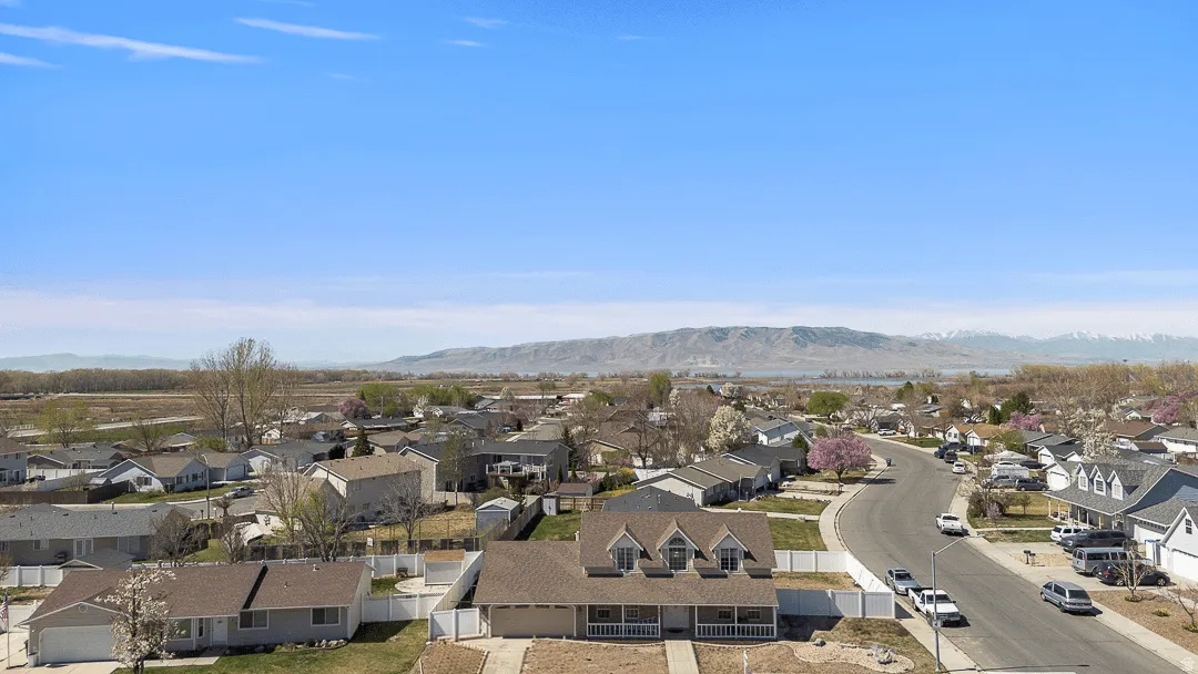 Suburban setting featuring a curved street, established residential properties, and distant mountains