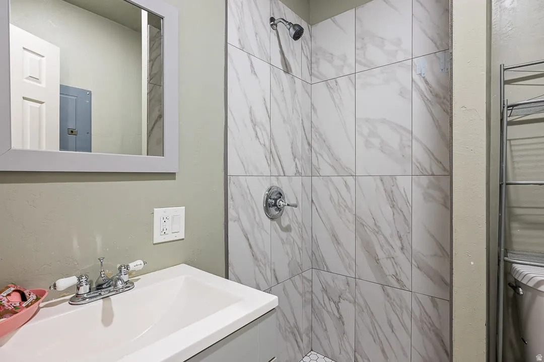 Shower with large format marble-look tile surround and hexagonal floor tiles
