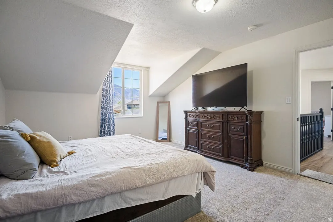 Carpeted room featuring a window with mountain scenery, sloped ceilings, and a flush mount ceiling light fixture
