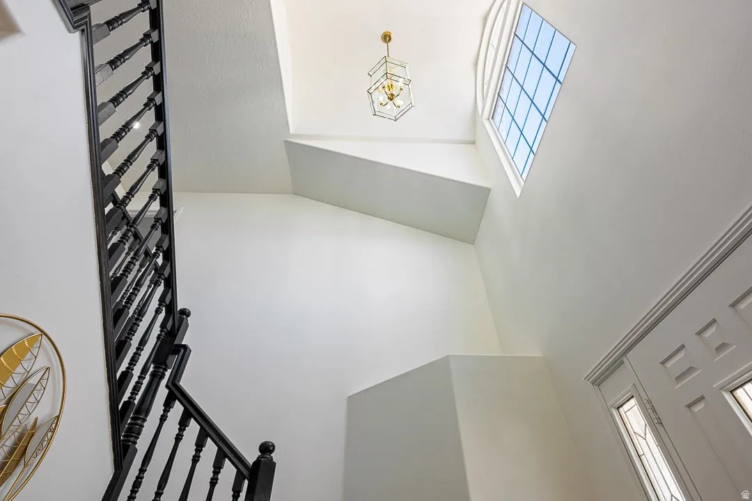 Two-story entryway featuring a prominent black staircase with decorative balusters, a multi-paned transom window, and a central ceiling light fixture