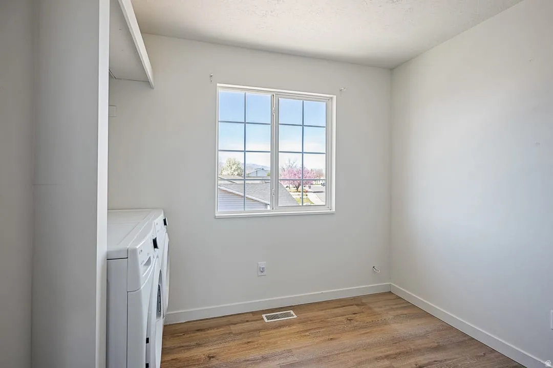 Bright room with a grid-paned window, wood-finish flooring, white baseboards, built-in shelving, and white walls