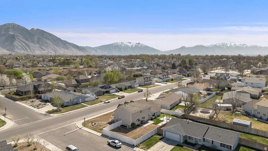 Aerial perspective showcasing a residential neighborhood with distant mountain ranges, some with snow-capped peaks