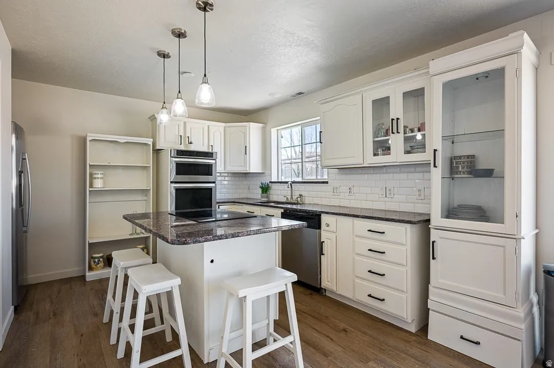 Kitchen featuring white cabinetry, a central island with granite countertop, and wood-finish flooring