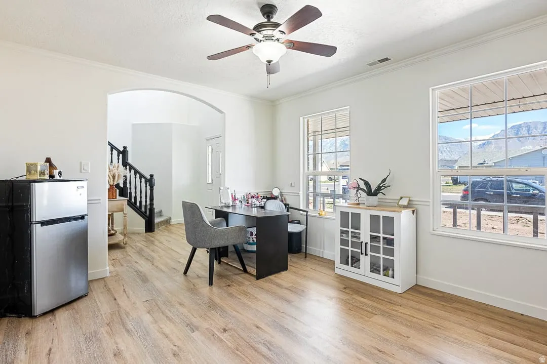 Bright interior space with wood-finish flooring, white walls, and a ceiling fan