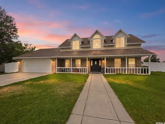 Two-story residence featuring a covered front porch, dormer windows, and an attached two-car garage