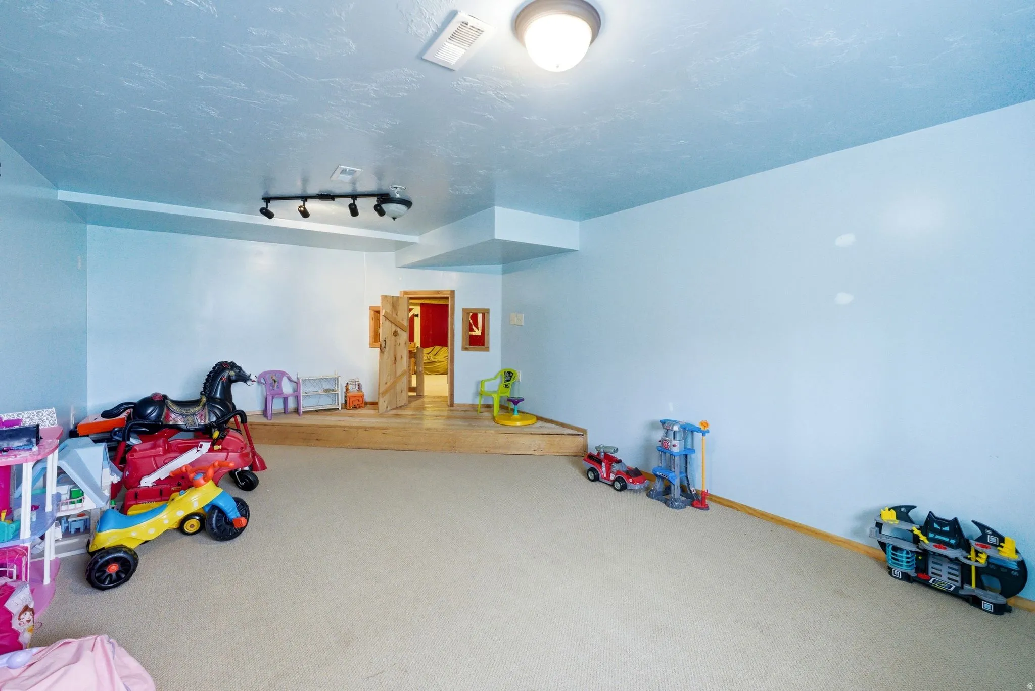 Carpeted room featuring light blue walls and a multi-level wooden platform