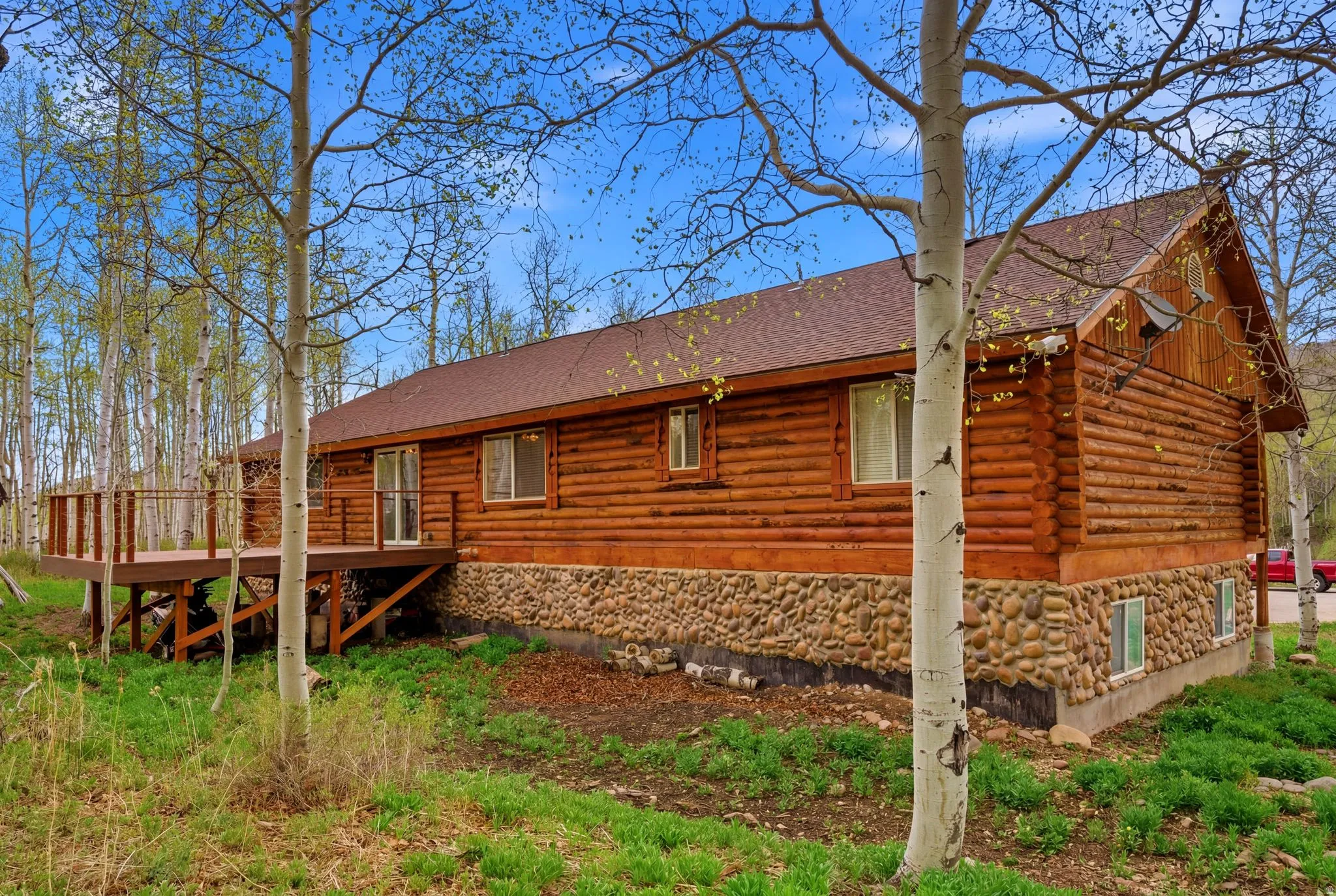 Log-style home featuring a stone foundation and a private deck