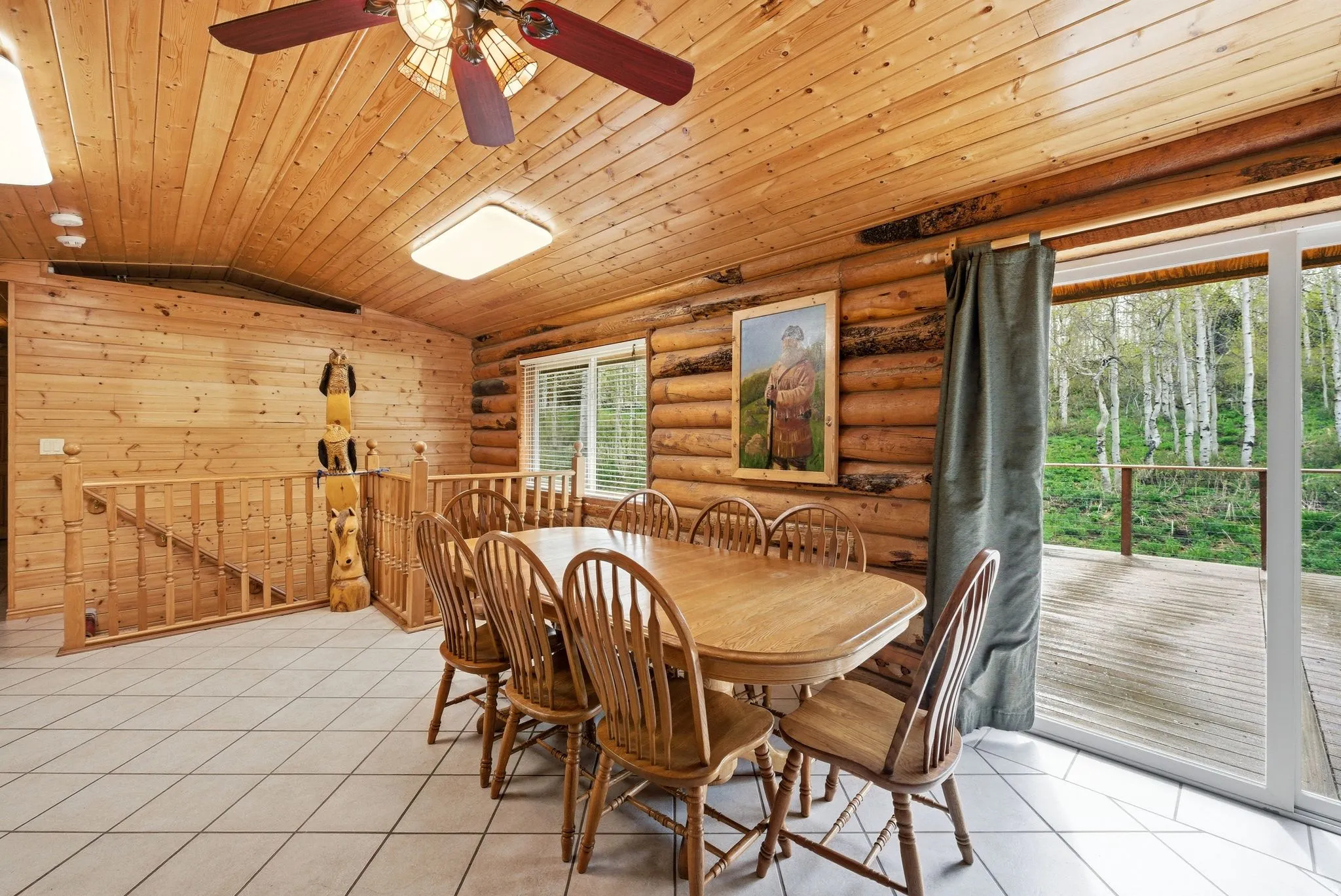 Dining area featuring log cabin walls, wood-paneled ceiling, ceiling fan with integrated lighting, and tile flooring