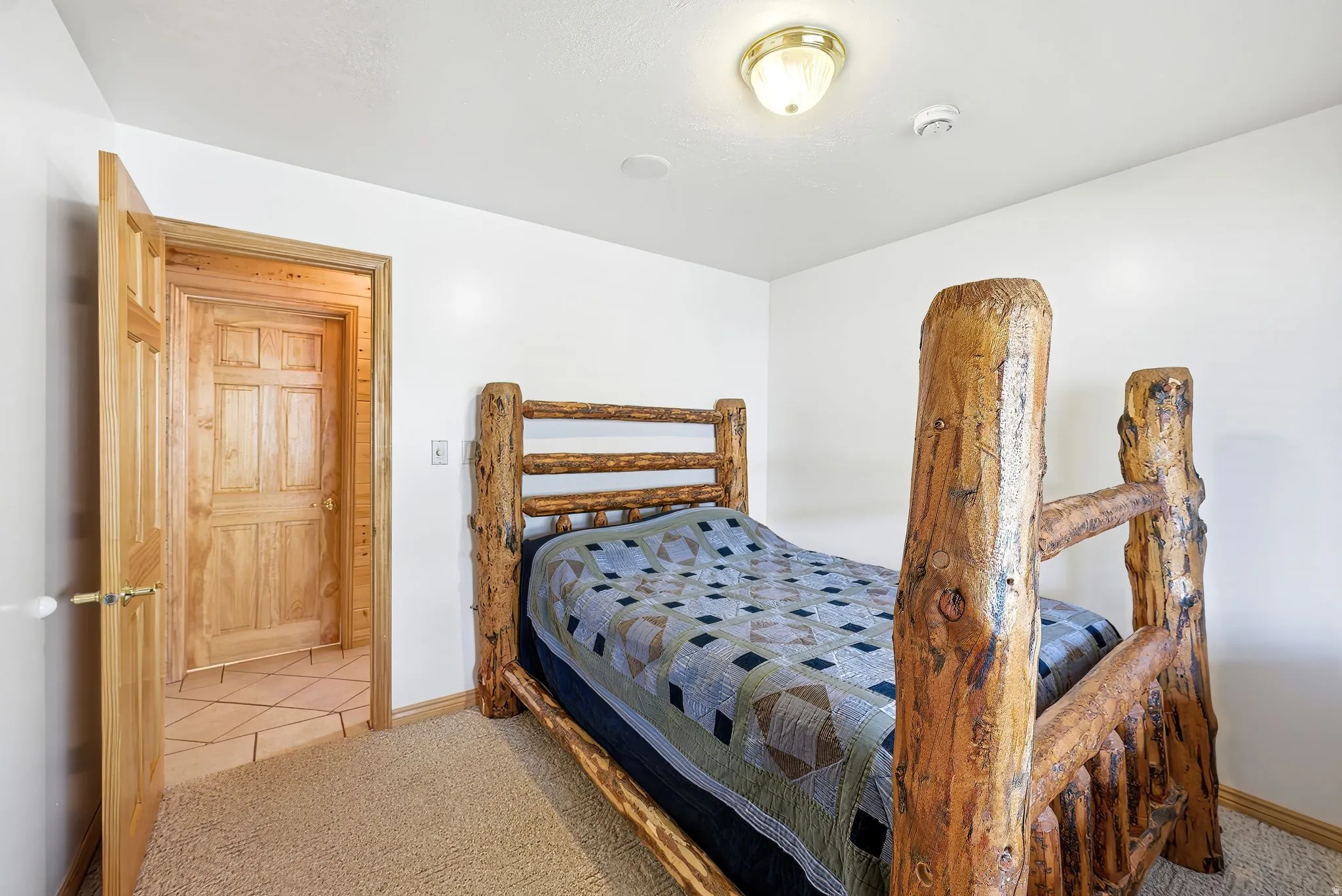 Wall-to-wall carpeting in a room featuring a natural wood door with brass hardware
