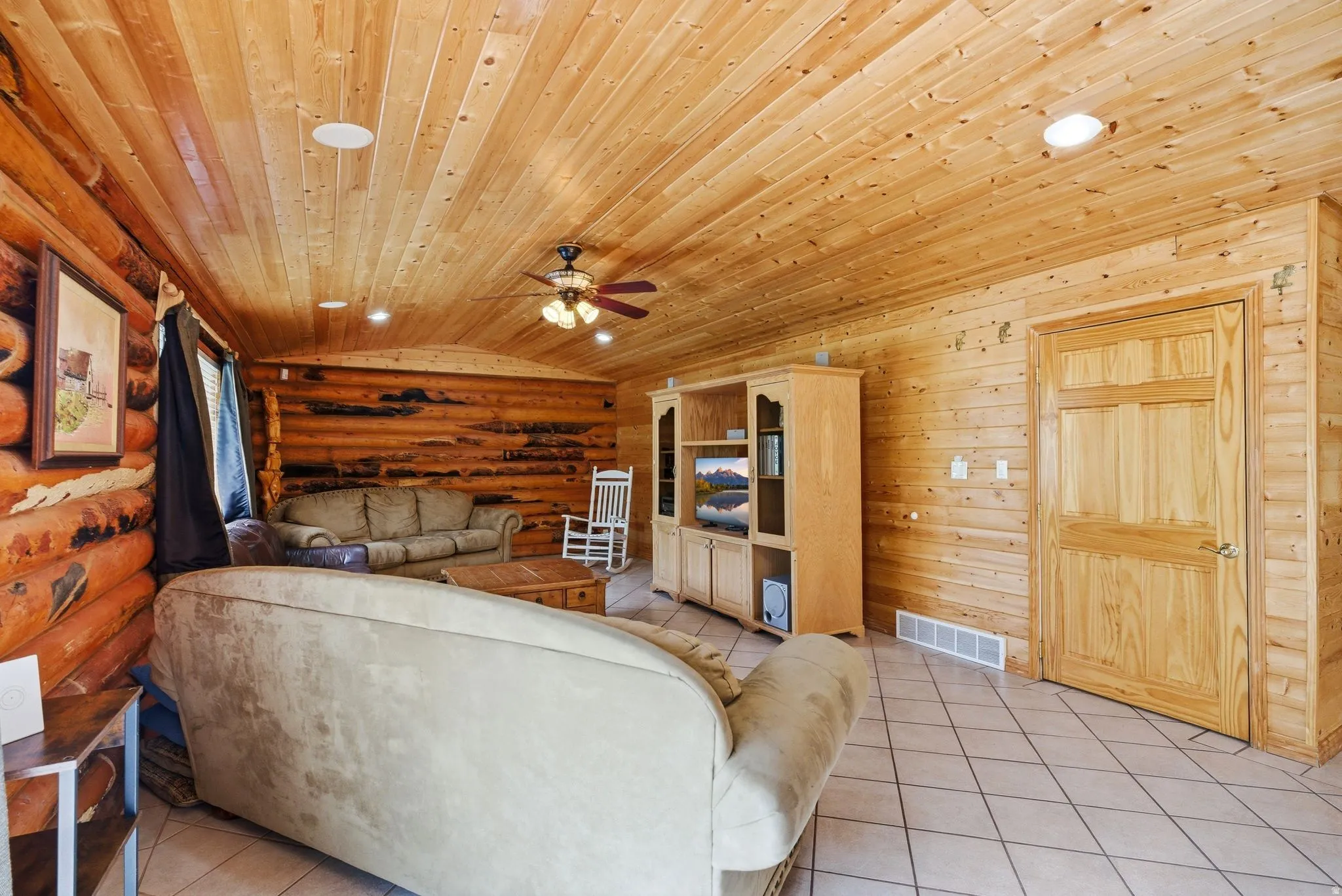Spacious living area featuring wood-finish walls, a wood-finish ceiling, and tile flooring