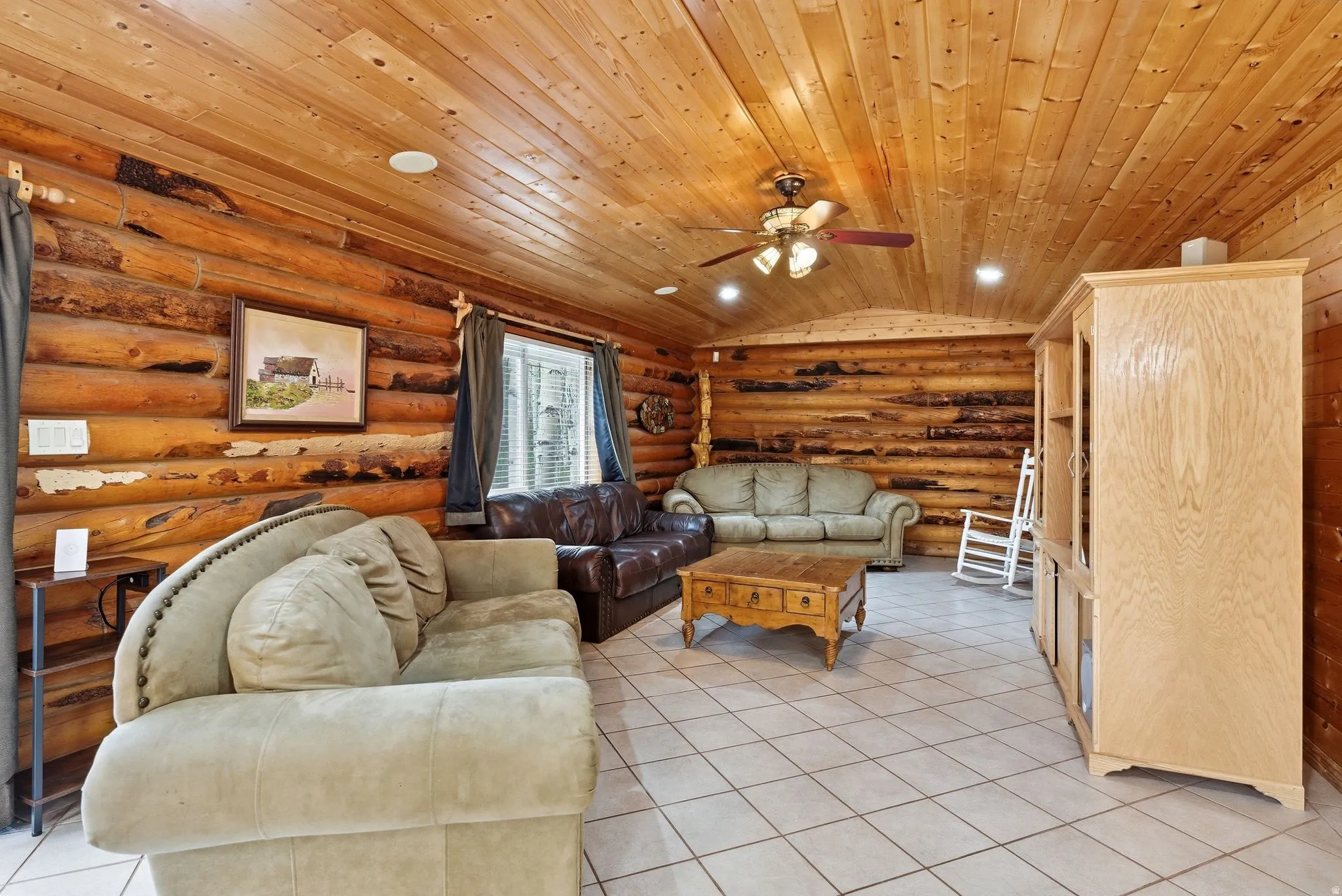 Spacious room featuring log-style walls and a wood-paneled ceiling