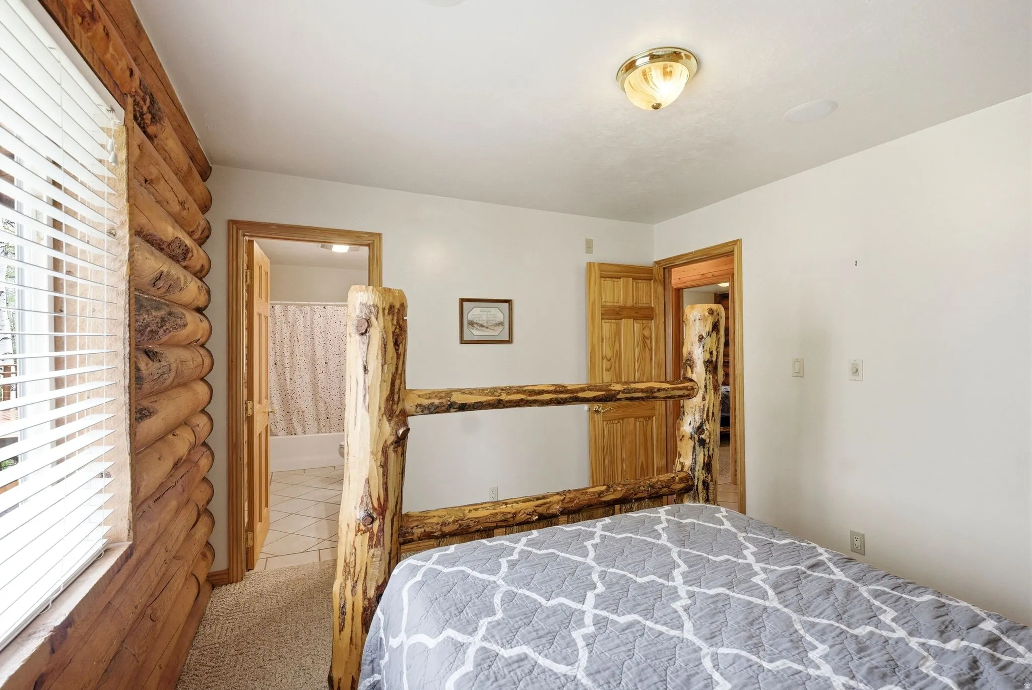 Interior room featuring log construction accent wall, carpeted flooring, and a white ceiling with a flush-mount light fixture