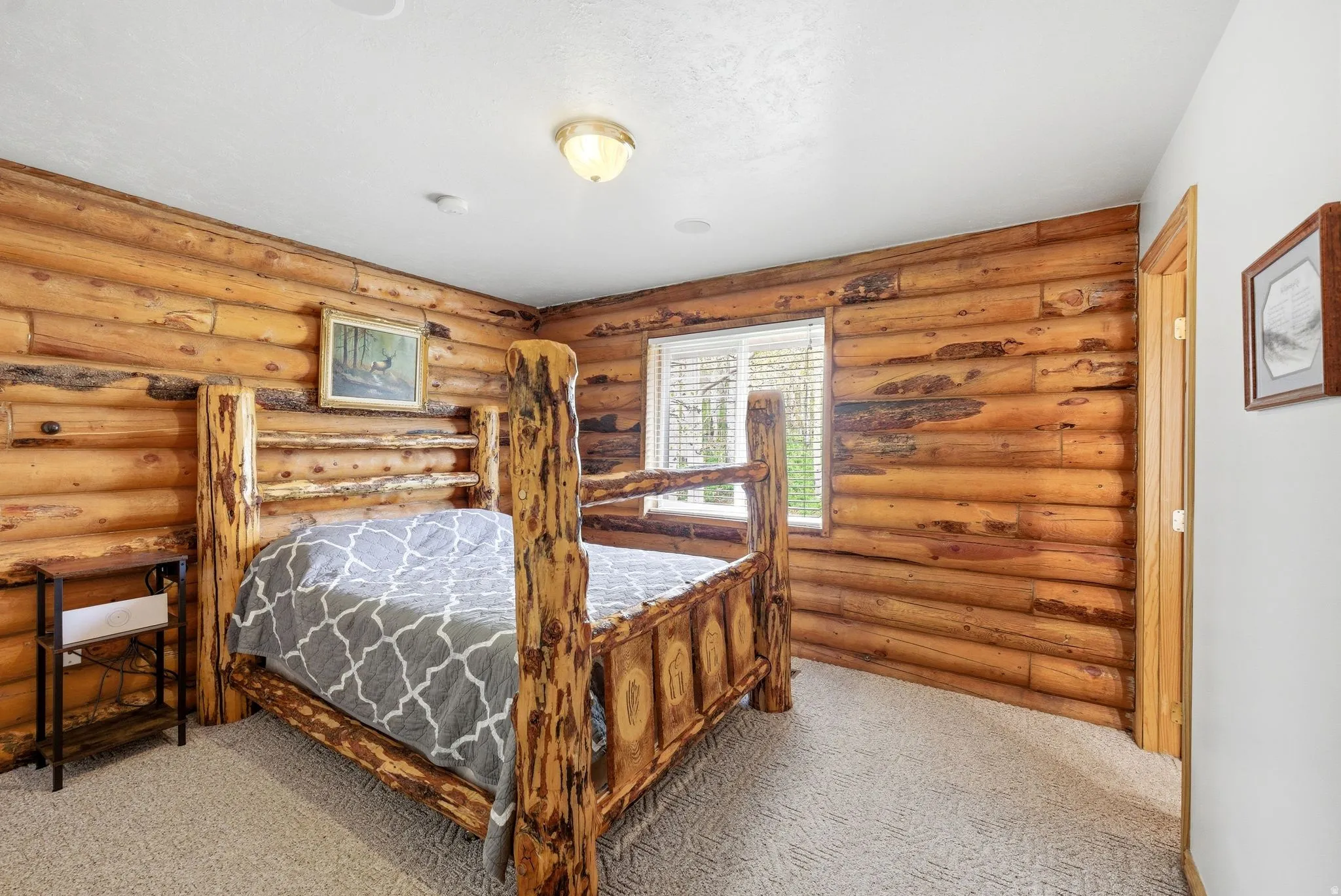 Room featuring log walls, light-colored carpet flooring, white ceiling, and a window with blinds