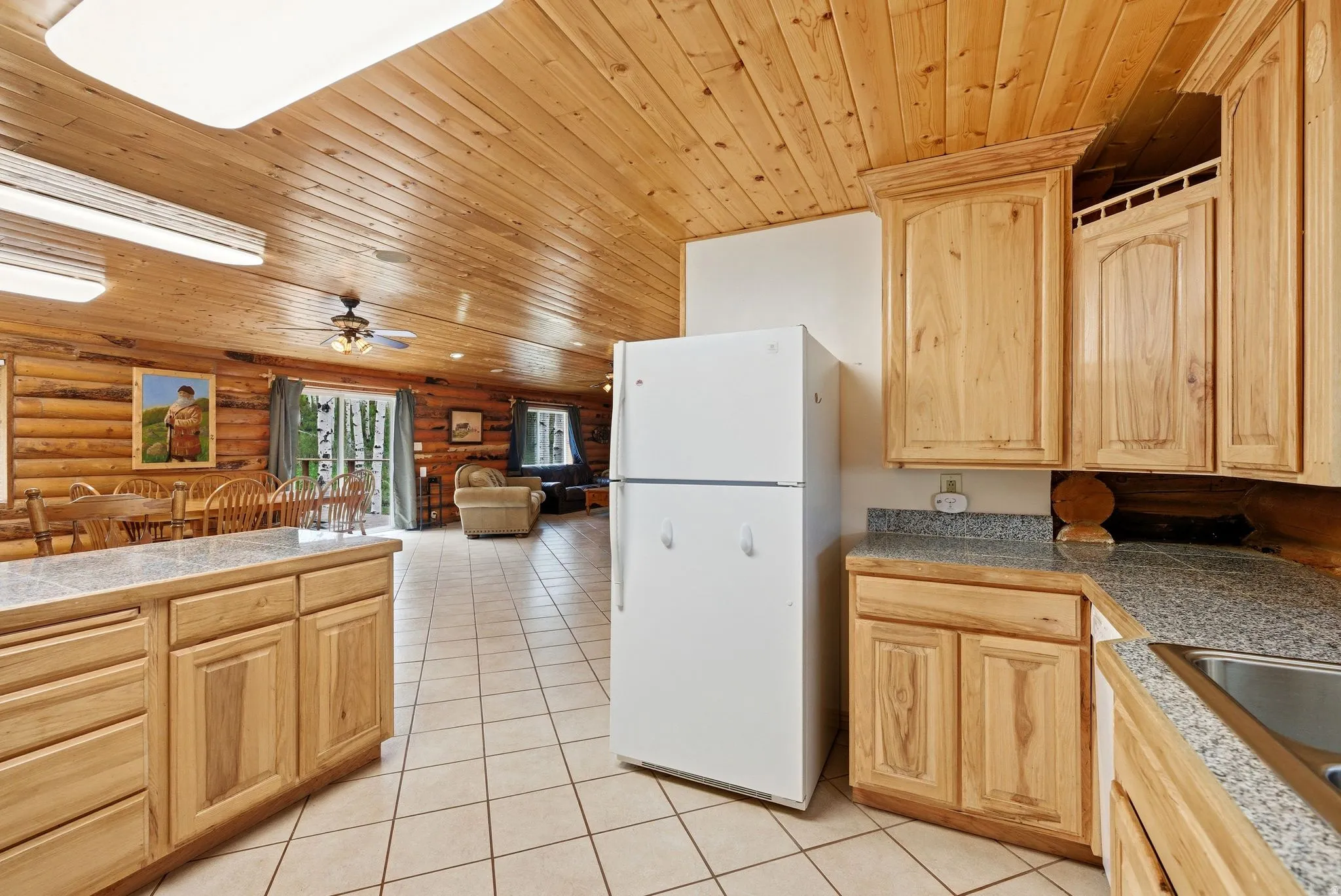 Kitchen area featuring light wood cabinetry, stone-look countertops, and a white refrigerator