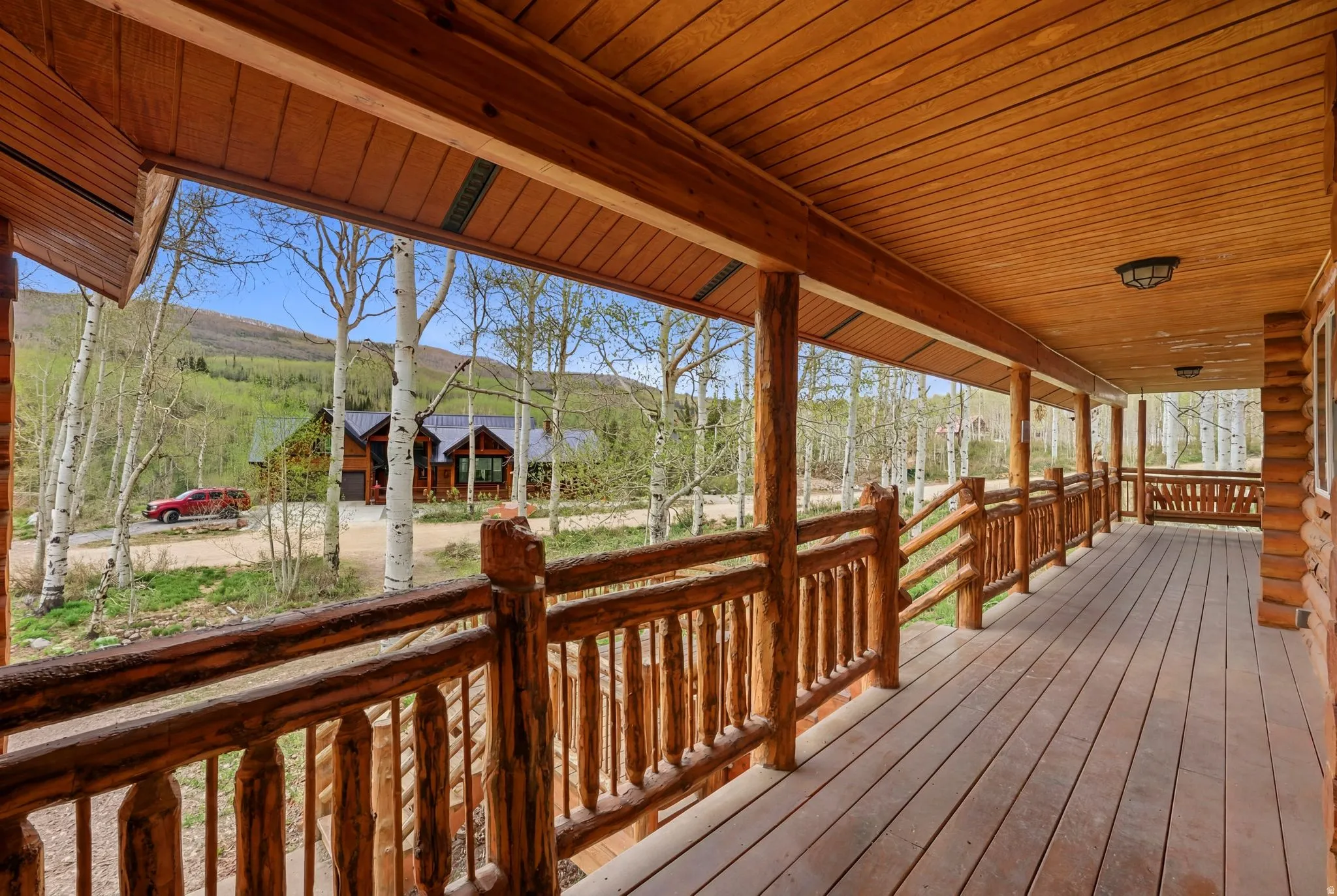 Expansive wood-finish porch featuring rustic log railings and a natural wood plank floor