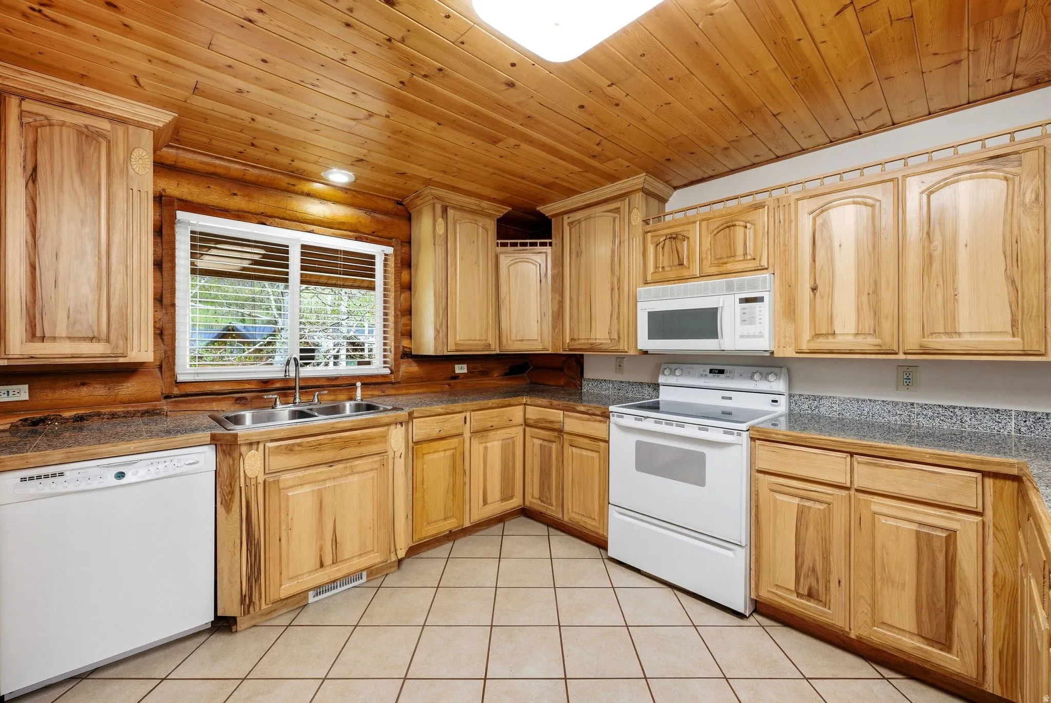 Kitchen featuring extensive wood cabinetry, wood-paneled ceiling, and tiled flooring