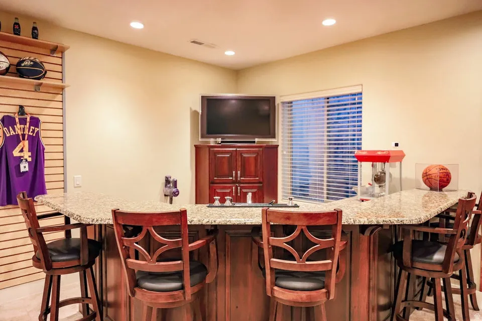Custom bar featuring a granite-style countertop, recessed lighting, and built-in cabinetry