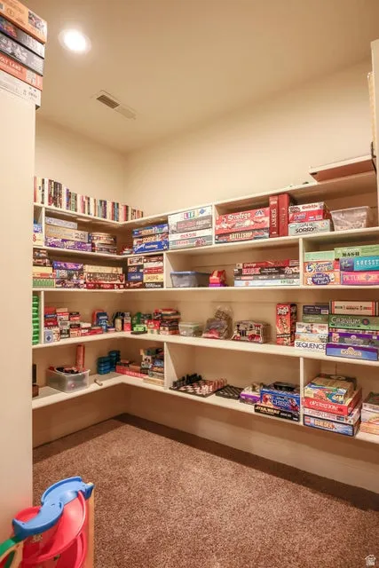 Built-in shelving with ample storage, recessed ceiling lighting, textured carpet flooring, and a neutral wall palette