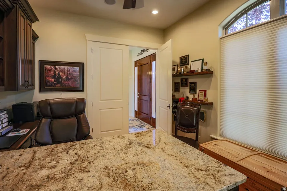 Spacious interior room featuring a large granite-finish desk surface, ceiling-mounted light fixture, and an arched transom window with a privacy blind