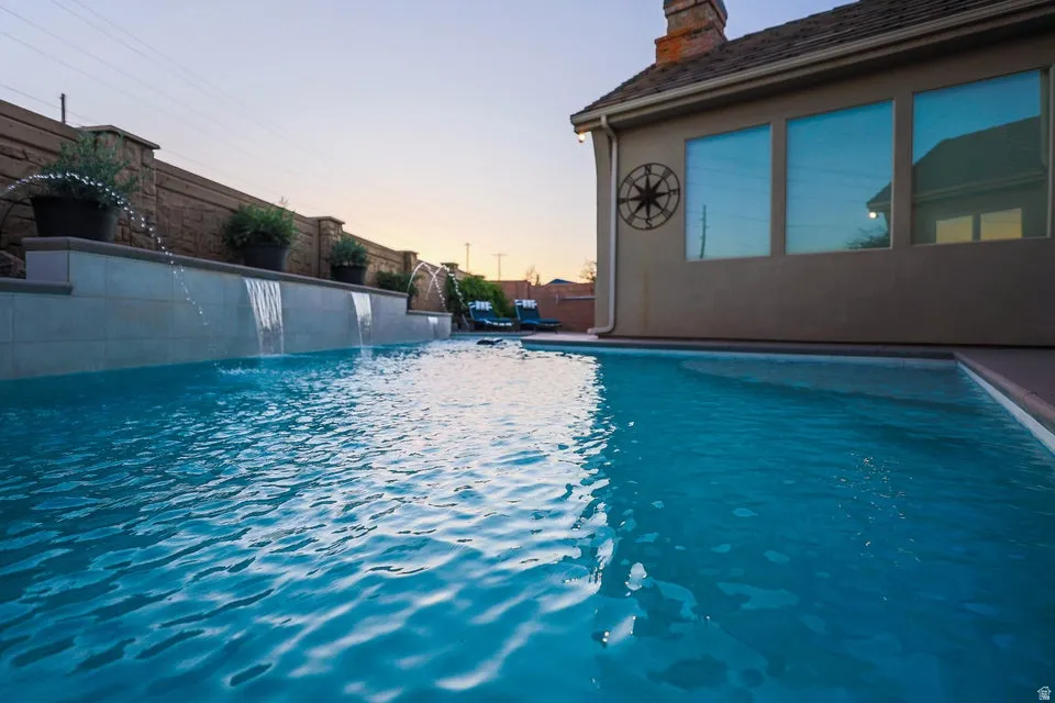 In-ground swimming pool featuring multiple water features, including cascading waterfalls and fountain jets