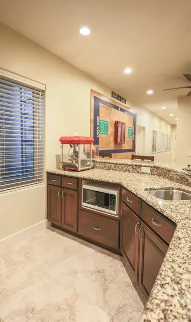 Kitchenette featuring granite countertops, wood cabinetry, stainless steel sink, and recessed lighting