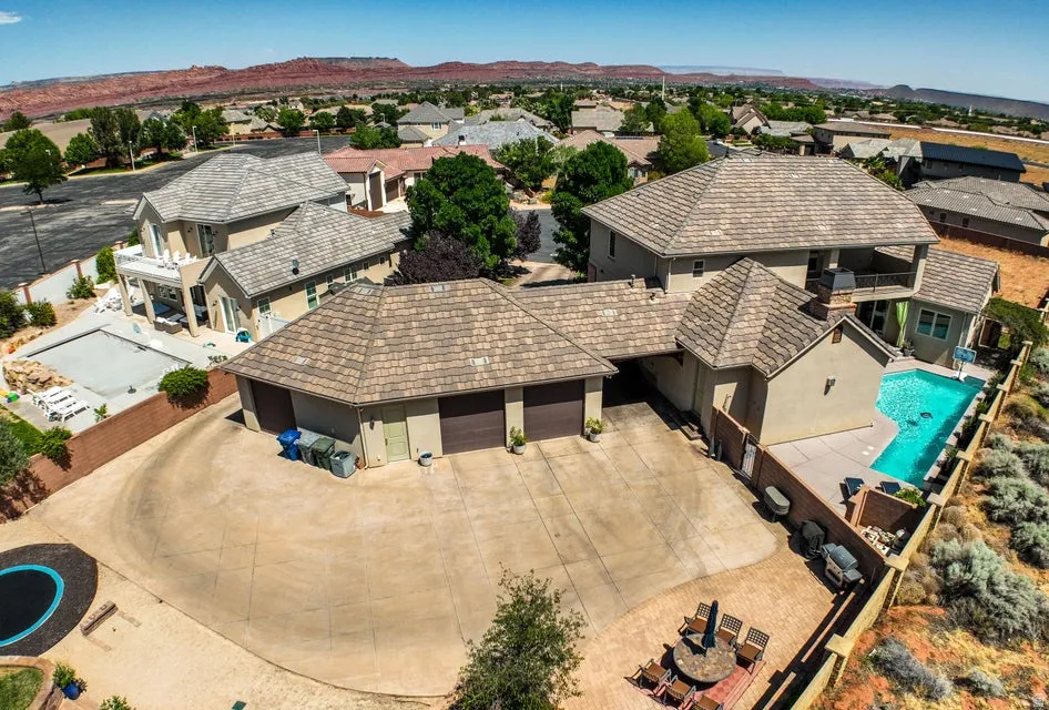 Expansive property featuring a multi-level residence with two distinct swimming pools and a large paved driveway