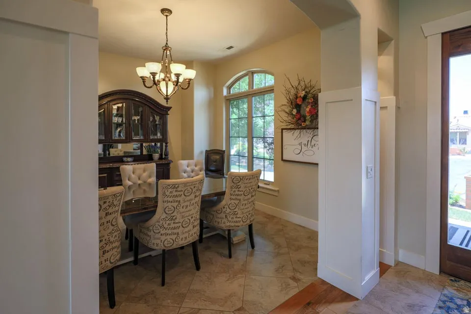 Dining area featuring a decorative chandelier, arched window, and tile flooring